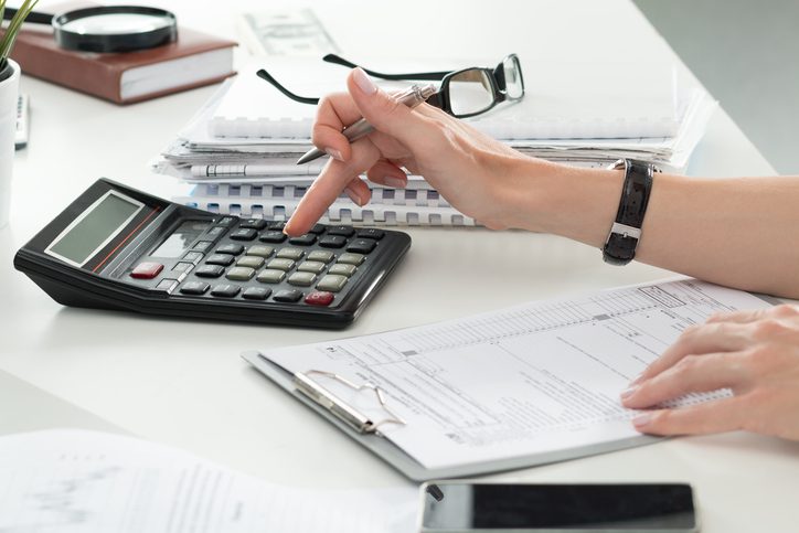 Martinson & Carter, CPAs, PA | hands on a desk using a calculator and holding a pair of glasses and a pen